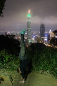 Handstand Steph on top of Elephant Mountain overlooking the Taipei skyline and 101 Taipei.